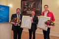 Landrat Hans-Jürgen Petrauschke, Thomas Tscheuschner und Christoph Claßen mit Blumensträußen und Urkunden in den Händen