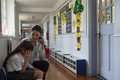 Lehrerin spricht mit einem weinenden Mädchen auf einem Schulflur.