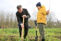 Landrat Hans-Jürgen Petrauschke und ein Kind pflanzen einen Baum