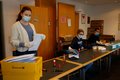 Mitarbeiterinnen verpacken Schutzmasken in Briefumschläge
