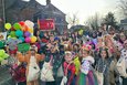 Gruppe kostümierter Kinder. Im Hintergrung bunte Luftballons.