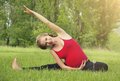 Schwangere Frau macht Gymnastikübungen auf einer Wiese
