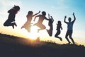 Symbolbild: Gruppe junger Menschen springt in die Luft. Sonnenuntergang im Hintergrund.  