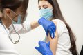 Symbolbild: Ärztin verabreicht Spritze in Oberarm einer jungen Frau