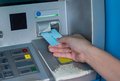 Eine Hand führt eine EC-Karte in einen Automaten.