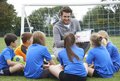 Kinder eines Fußballvereins sitzen im Kreis um ihren Trainer