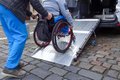 Ein Rollstuhlfahrer wird über eine Rampe in ein Fahrzeug geschoben.