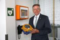 Landrat Hans-Jürgen Petrauschke hält einen Defibrillator in den Händen