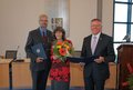 Landrat Hans-Jürgen Petrauschke Regina Hoppe-Kresse (mit Blumen) und Martin Kresse, ausgezeichnet mit dem Bundesverdienstkreuz,  stehen lächelnd nebeneinander. 