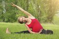 Schwangere Frau macht auf einer Wiese Gymnastikübungen.