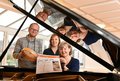Markus Wehner, Juliane Ries und Ruth Braun-Sauerwein sitzen an einem Klavier und zeigen einen Flyer